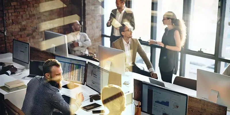 Six people in an office surrounded by computer monitors