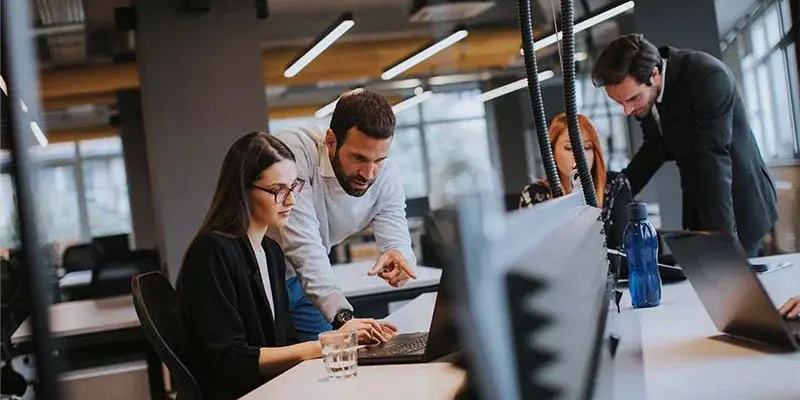 Six people in an office surrounded by computer monitors